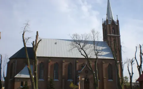 Sanktuarium w Swarzewie, ceglany kościół z wysoką wieżą, otoczony drzewami o nagich gałęziach.