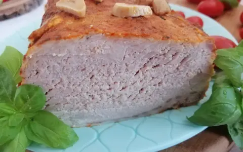 Soczysty schab pieczony w mleku, z czosnkiem i bazylią, prezentuje się apetycznie na talerzu.