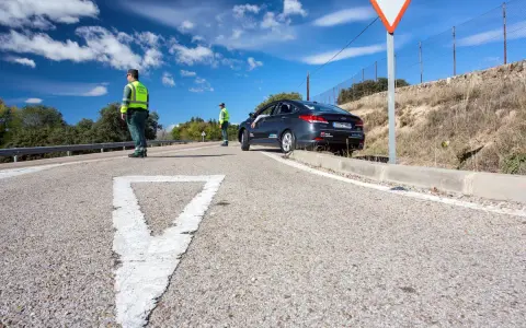 Agentes de tráfico controlan la circulación en una carretera. Un coche se detiene, quizás preguntándose cuánto tarda en llegar una multa.