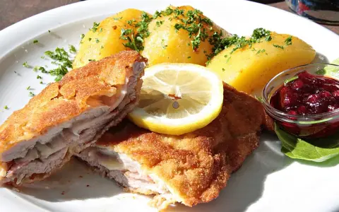 Kotlet po szwajcarsku z ziemniakami, cytryną i żurawiną. Pyszne danie na talerzu.