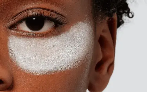 Primo strato di cipria prima del fondotinta, evidenzia la texture della pelle e la preparazione per un makeup impeccabile.
