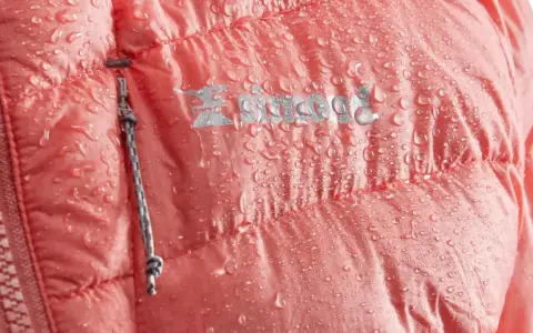 Wodoodporna kurtka z koralowym, zbitym puchem. Kropelki wody na materiale i logo marki.