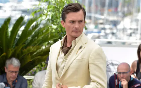 Hombre con un impecable corte de pelo old money, viste un traje de lino color crema y un pañuelo de seda.