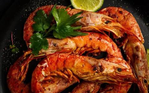 Gambones a la plancha, jugosos y dorados, servidos con perejil fresco y rodajas de lima. ¡Un manjar irresistible!