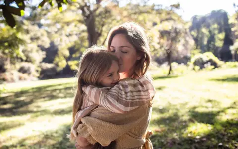 Mutter küsst ihr Kind zärtlich im Arm. Ein Moment voller Liebe, der die Essenz von gentle parenting deutsch widerspiegelt.
