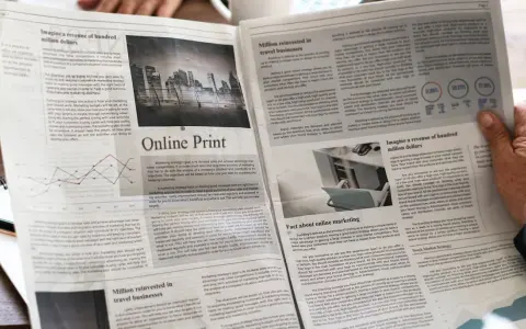 Manos sostienen un periódico con artículos sobre marketing y finanzas, impreso en gramaje papel normal.