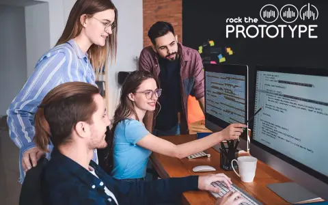 Ein Team von vier Personen arbeitet im **mob programming** an einem Projekt. Sie blicken auf zwei Bildschirme mit Code.
