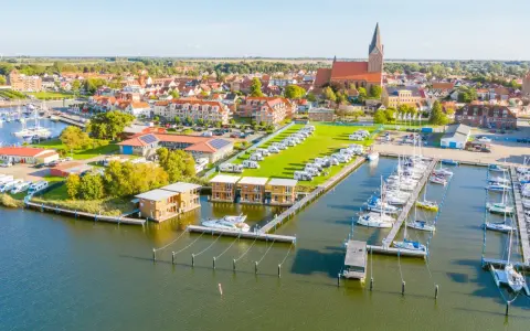 Blick auf Barth an der Ostsee mit Yachthafen, Wohnmobilstellplätzen und modernen Ferienhäusern am Wasser.