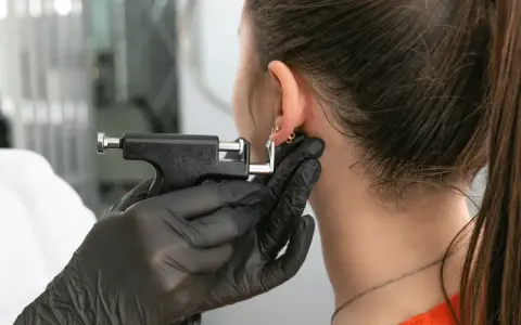 Profesjonalne przekłuwanie ucha. Widoczne spuchnięte ucho po przebiciu chrząstki, z nową biżuterią.
