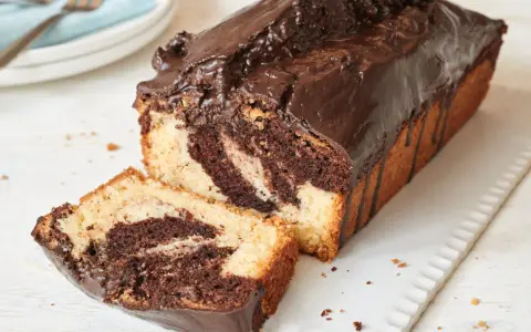 Saftiger Marmorkuchen, frisch aus dem Airfryer, mit Schokoladenglasur und einer angeschnittenen Scheibe.