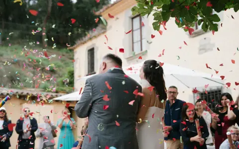 Novios bajo una lluvia de confeti en forma de corazón. Los invitados lanzan confeti, creando un ambiente festivo, perfecto para las canciones de boda.