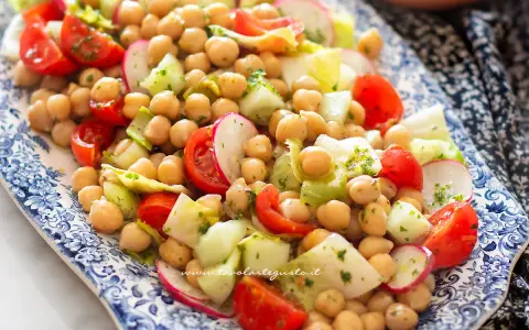 Un'insalata di legumi colorata e fresca con ceci, pomodorini, cetrioli e ravanelli, condita con erbe aromatiche.