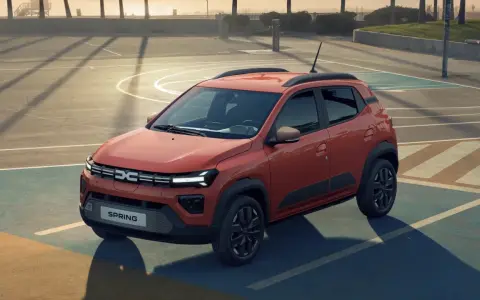 Pomarańczowy Dacia Spring na boisku. Sprawdź atrakcyjną dacia spring cena i odkryj jego możliwości.