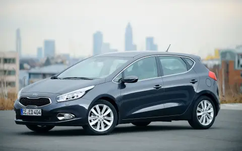 Ciemnoszary Kia Ceed 1.6 benzyna stoi na tle miejskiego krajobrazu.