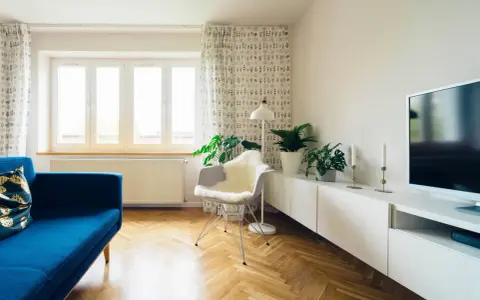 Jasna podłoga w jodełkę świetnie komponuje się z niebieską kanapą i białymi meblami. To inspiracja, jak dobrać kolor podłogi do mebli, tworząc harmonijną przestrzeń.