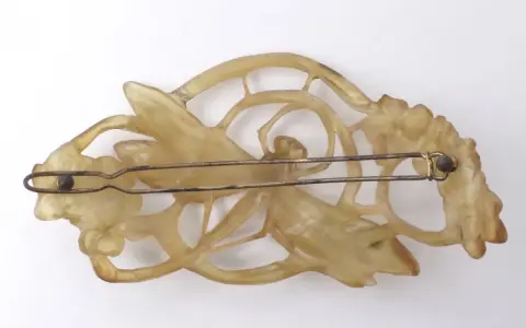 Pince à cheveux Art Nouveau en corne sculptée, évoquant le style de Lucien Gaillard, avec des motifs floraux et une libellule.