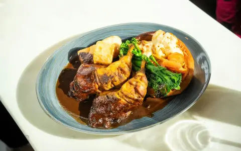 Pyszny niedzielny obiad: pieczone udka kurczaka w sosie, pieczone ziemniaki, brokuły i kalafior zapiekany w Yorkshire pudding.