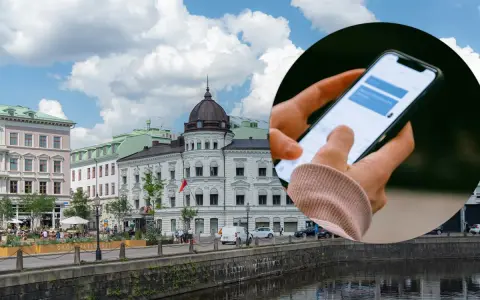 Dłoń trzymająca smartfon z widocznym oknem czatu na tle miejskiego krajobrazu z budynkami i rzeką.