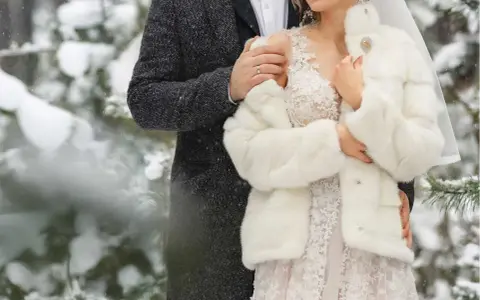 Para młoda w objęciach, otulona śniegiem i miłością. Romantyczne zimowe wesele w lesie.