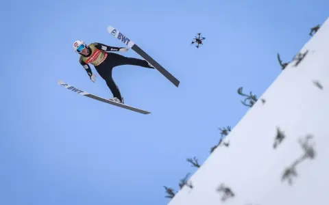 Skoczek narciarski w locie, z dronem w tle. Zastanawiasz się, ile waży skoczek narciarski, by osiągnąć taką odległość?