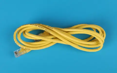 Un câble Ethernet jaune enroulé sur fond bleu. Il est marqué "UTP Cat5e BI-COM". Un bon choix pour votre réseau.