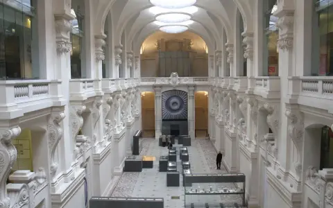 Interior del museo de artes decorativas, con arcos, balcones y vitrinas exhibiendo objetos.