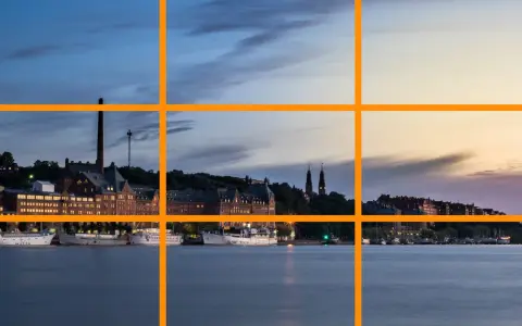 Un paysage urbain au crépuscule, avec des bâtiments historiques et des bateaux le long de l'eau. Un excellent exemple pour un tuto photographie sur la règle des tiers.