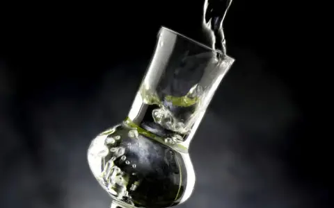 Klarer Grappa wird in ein Glas gegossen. Die Frage "wie viel prozent hat grappa" wird durch die klare Flüssigkeit und die Bläschen im Glas angedeutet.