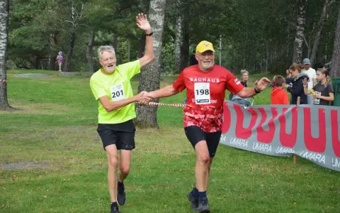 Två glada löpare, nummer 201 och 198, skakar hand vid målgången på kåsjön trail.