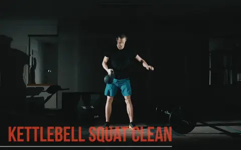 Man utför en kettlebell clean i ett mörkt gym.