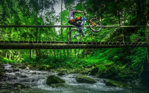 Rowerzysta na drewnianym moście nad potokiem, odkrywa nowe trasy rowerowe Zakopane.
