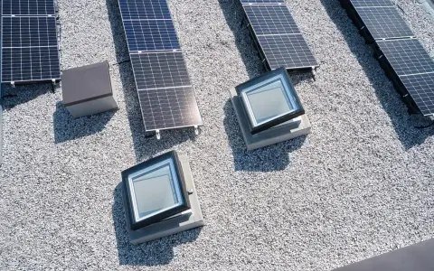 Vue aérienne d'une maison toit plat avec panneaux solaires et deux fenêtres de toit.
