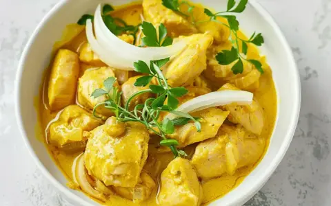 Kyckling i krämig currysås, perfekt för ett snabbt currysås recept. Garnerad med lök och persilja.