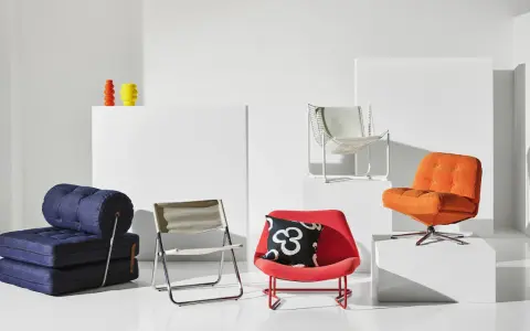 En samling möbler i 70-tals inredning: en blå bäddsoffa, en röd fåtölj med mönstrat kudde, en orange fåtölj och en vit metallstol.
