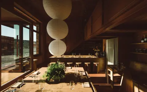 Gemütliches Restaurant in **Aerde Berlin** mit Holztischen, großen Papierlampen und Blick auf das Wasser.