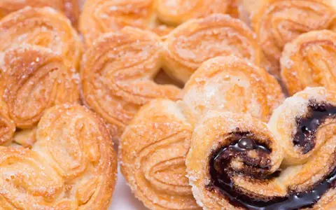 Deliciosas palmeritas de hojaldre espolvoreadas con azúcar. Algunas tienen un relleno de chocolate oscuro y brillante.