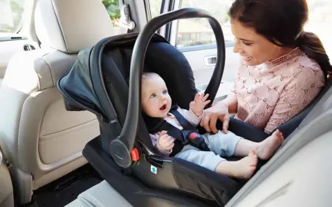 Uśmiechnięta mama patrzy na swoje dziecko w foteliku samochodowym. Ten fotelik dla dziecka do 20 kg zapewnia bezpieczeństwo maluchowi podczas podróży.