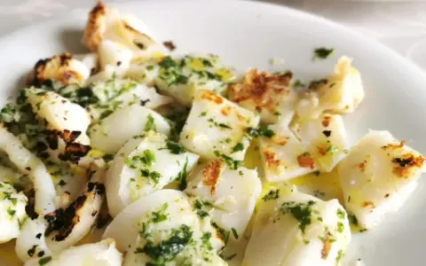 Sabrosa sepia a la plancha, cortada en trozos y aderezada con perejil fresco y aceite de oliva.