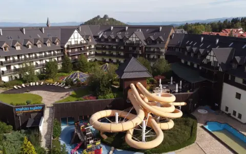 Karpacz hotel z aquaparkiem oferuje zjeżdżalnie i baseny. Widać też góry w tle.