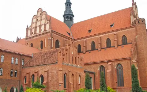 Majestatyczna pelplińska katedra z cegły, z charakterystycznymi dachami i wieżą, góruje nad otoczeniem.