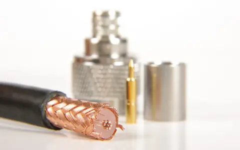 Przewód ekranowany z miedzianym oplotem, obok złoty pin i metalowe złącza.