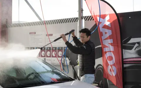 Man tvättar bilen med högtryckstvätt och Sonax glansschampo.