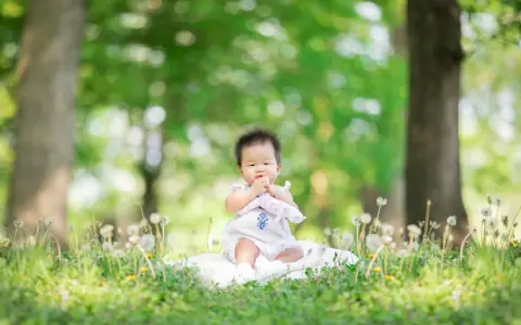 Dolce bimbo di 9 mesi seduto sull'erba, con soffioni e alberi sullo sfondo. Una foto che cattura la sua curiosità.