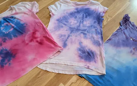 Batik mit Kindern: Drei bunte T-Shirts in Rosa, Lila und Blau, die nach einem kreativen Nachmittag aussehen.