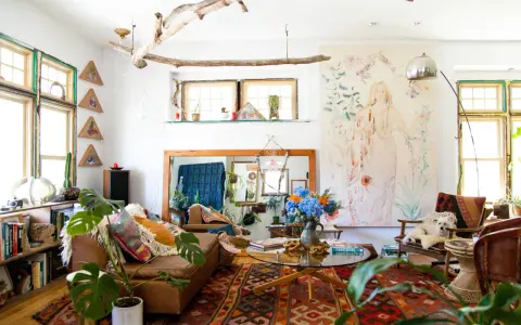Salon bohème, style kinfolk, avec tapis ethnique, canapé en cuir, plantes vertes et un tableau mural.