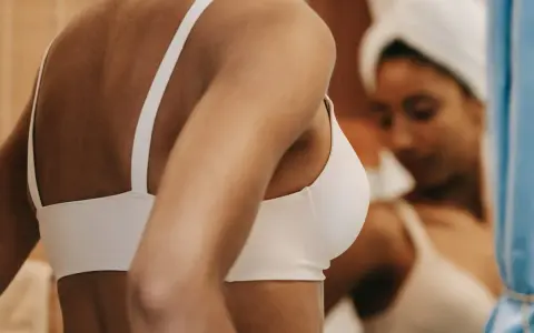 Donna con reggiseno stretto, forse per l'emozione o la tachicardia, si guarda allo specchio.
