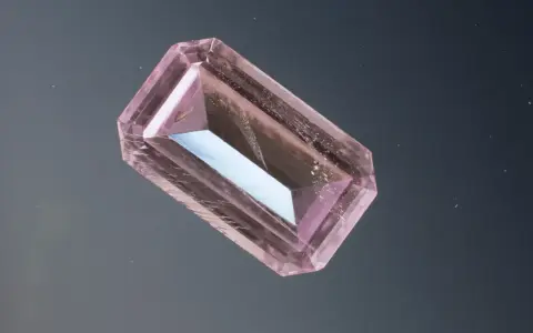 Un cristallo rosa sfaccettato, simile a uno smeraldo, fluttua su uno sfondo scuro. Un esempio di pietre più costose.