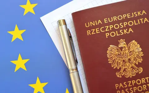Polski paszport, długopis i flaga Unii Europejskiej.