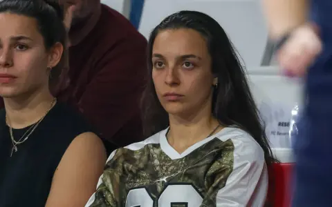 Natalia Padilla Bidas, zamyślona, siedzi na trybunach w koszulce z motywem kamuflażu.