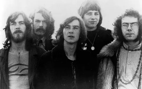 Cinq membres de King Crimson posent ensemble, arborant des coiffures et des vêtements typiques des années 70.